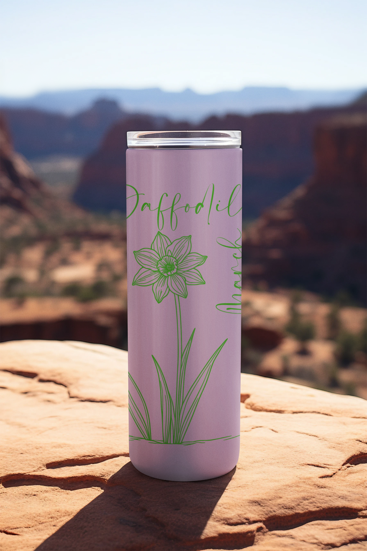 March birth flower tumbler with daffodil design on scenic rock ledge