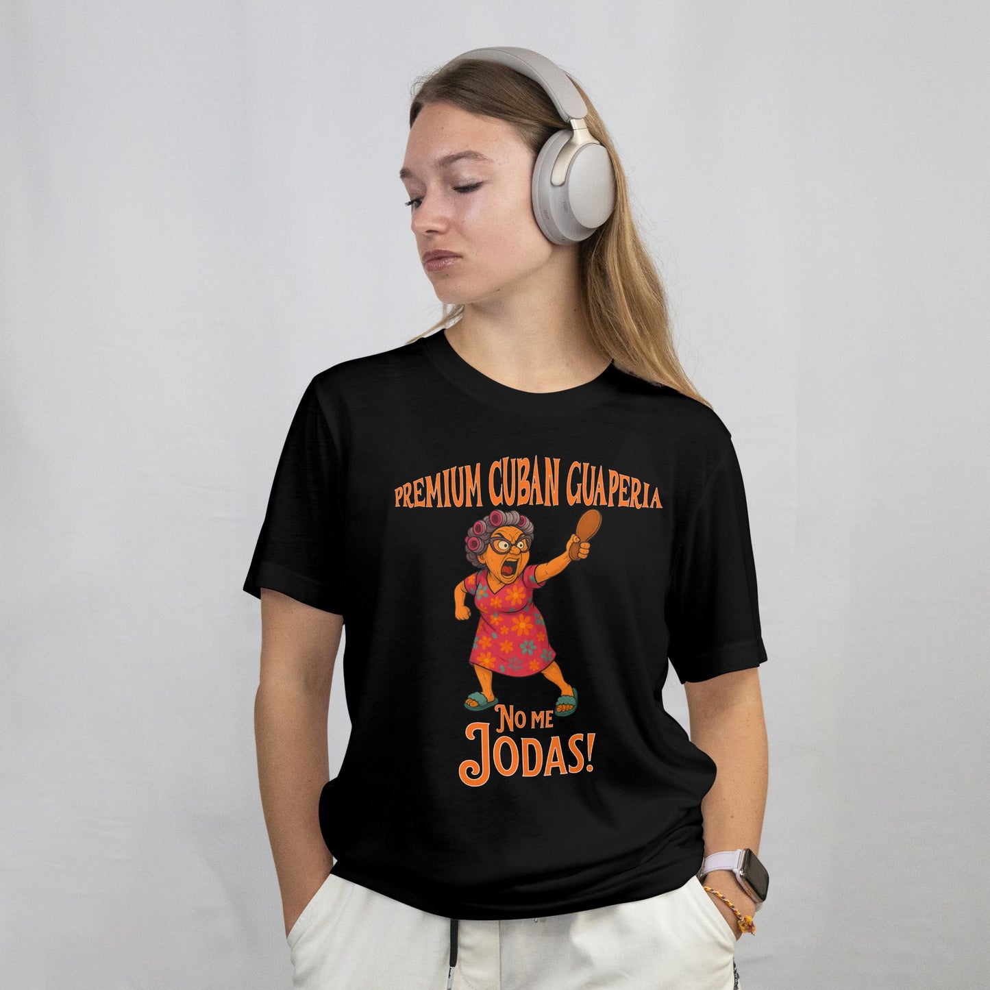 Person wearing a black t-shirt with colorful graphic and text, listening to music with headphones on a plain background