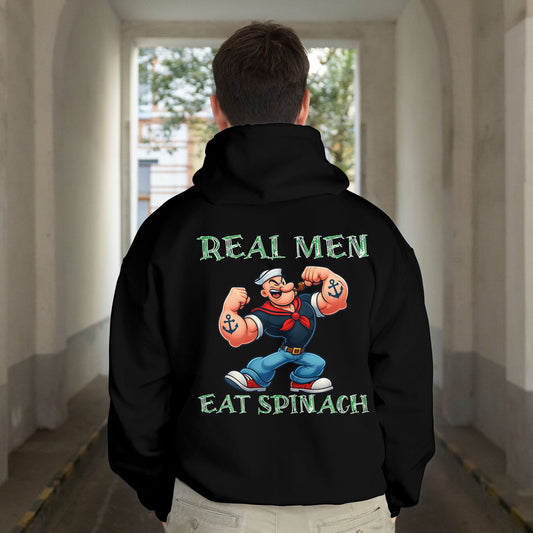 Person wearing a black hoodie with a cartoon character and text on the back, standing in a hallway.