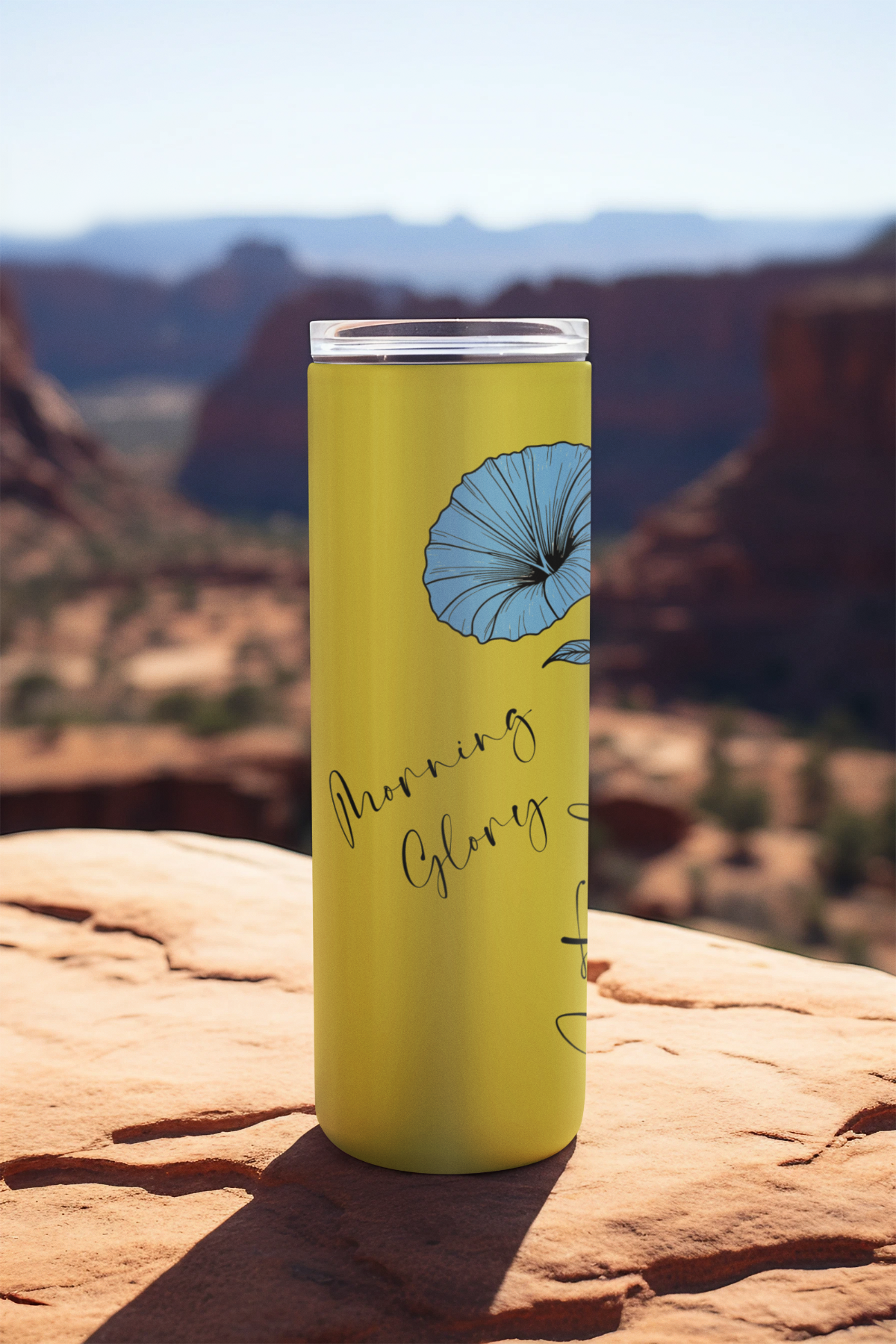 September Monthly Blooms 20oz tumbler placed on a rocky ledge with scenic backdrop