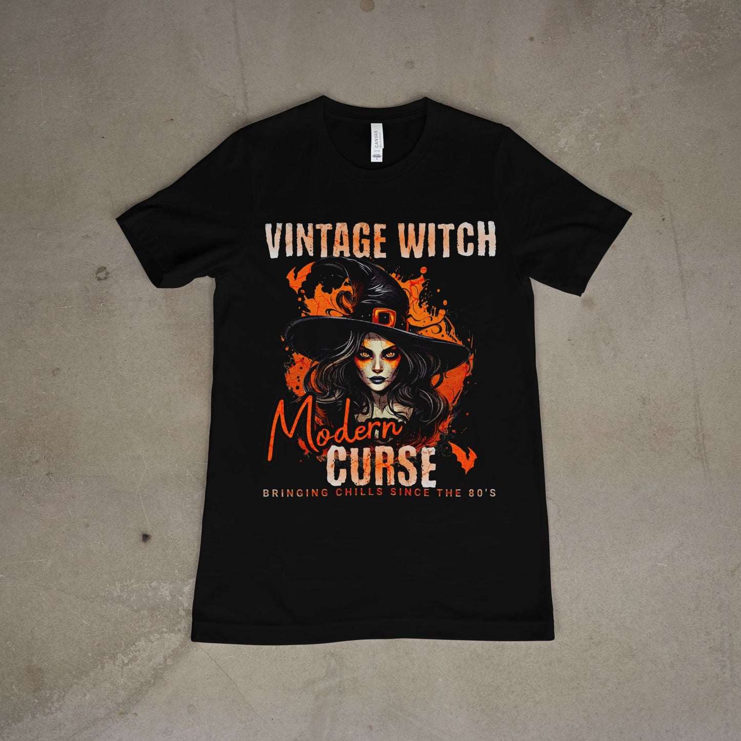 Black t-shirt with witch graphic and text on a concrete floor