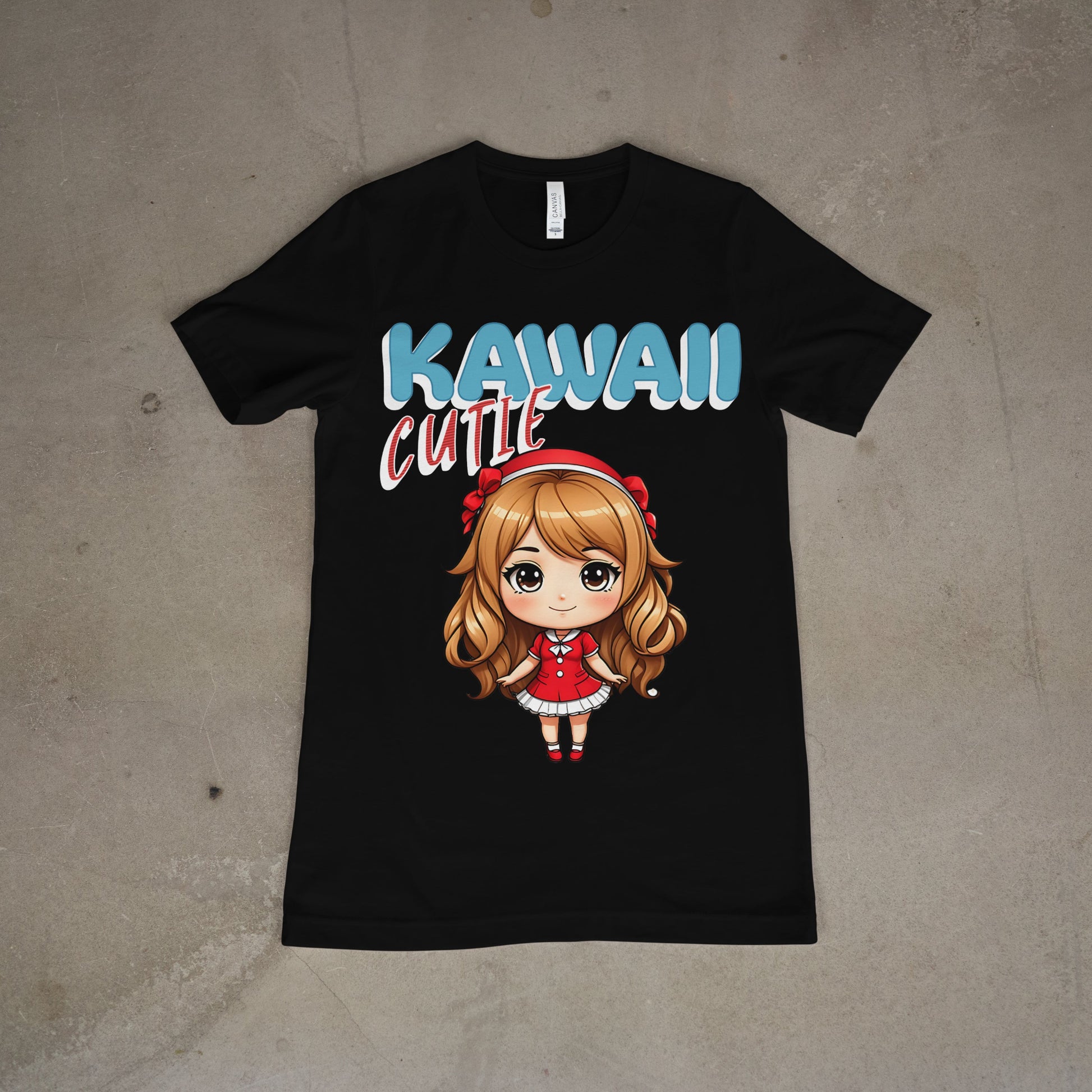 Black, women's graphic t-shirt featuring bold pastel text that says "Kawaii Cutie" in blue, pink, and white, laid flat on a concrete background.