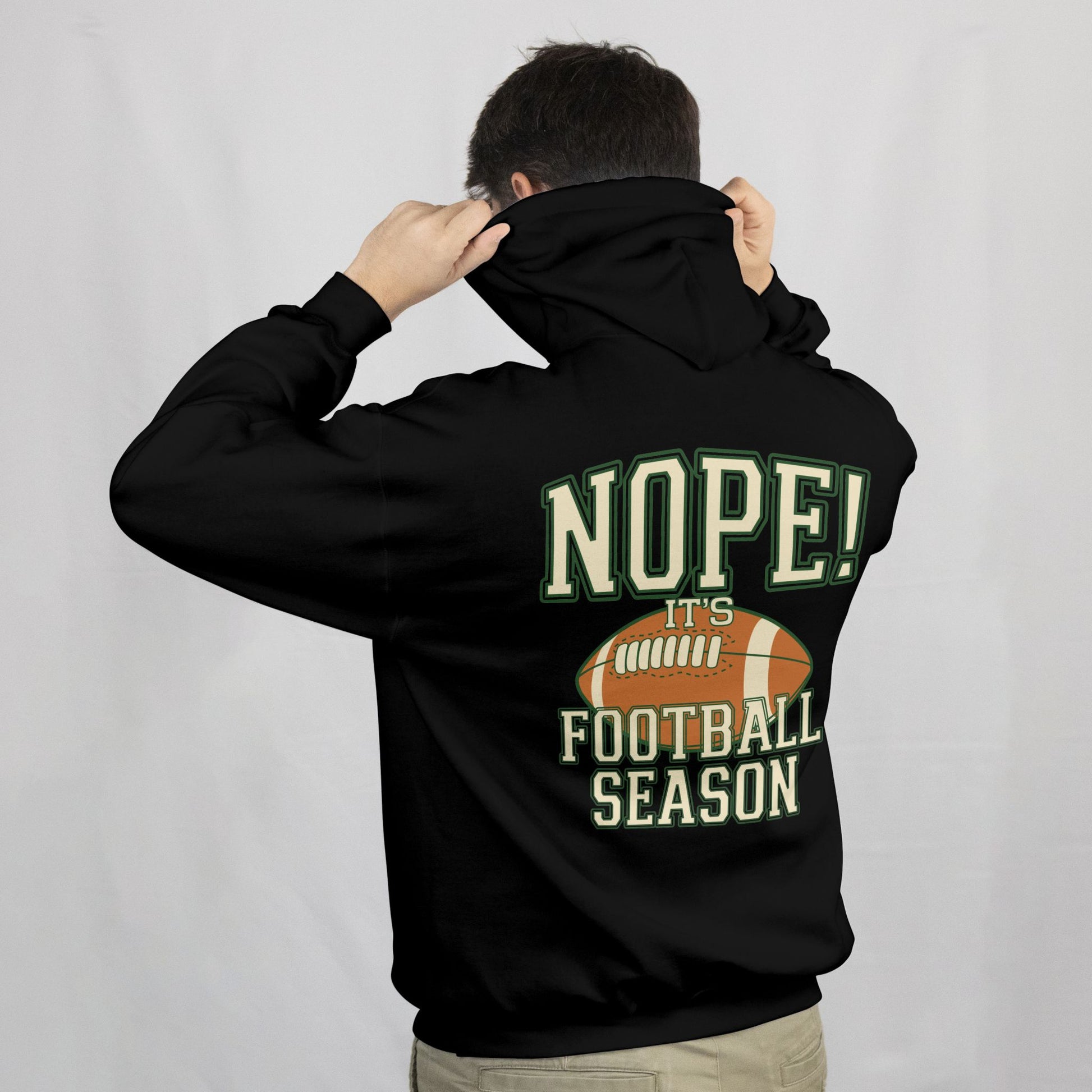 Person wearing a black hoodie with 'NOPE! It's Football Season' text and football graphic on the back.
