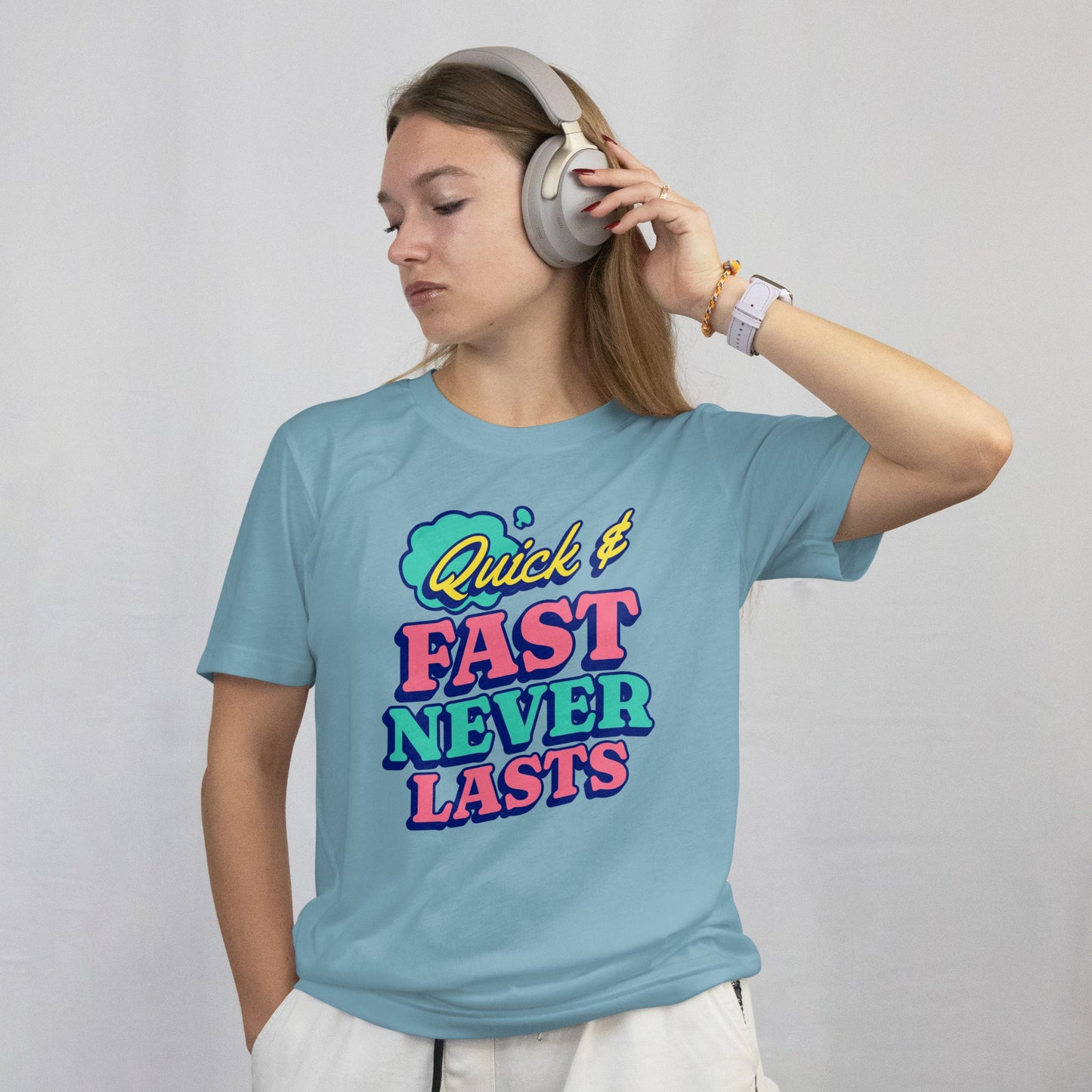 Person wearing a light blue t-shirt with colorful text and headphones on a plain background