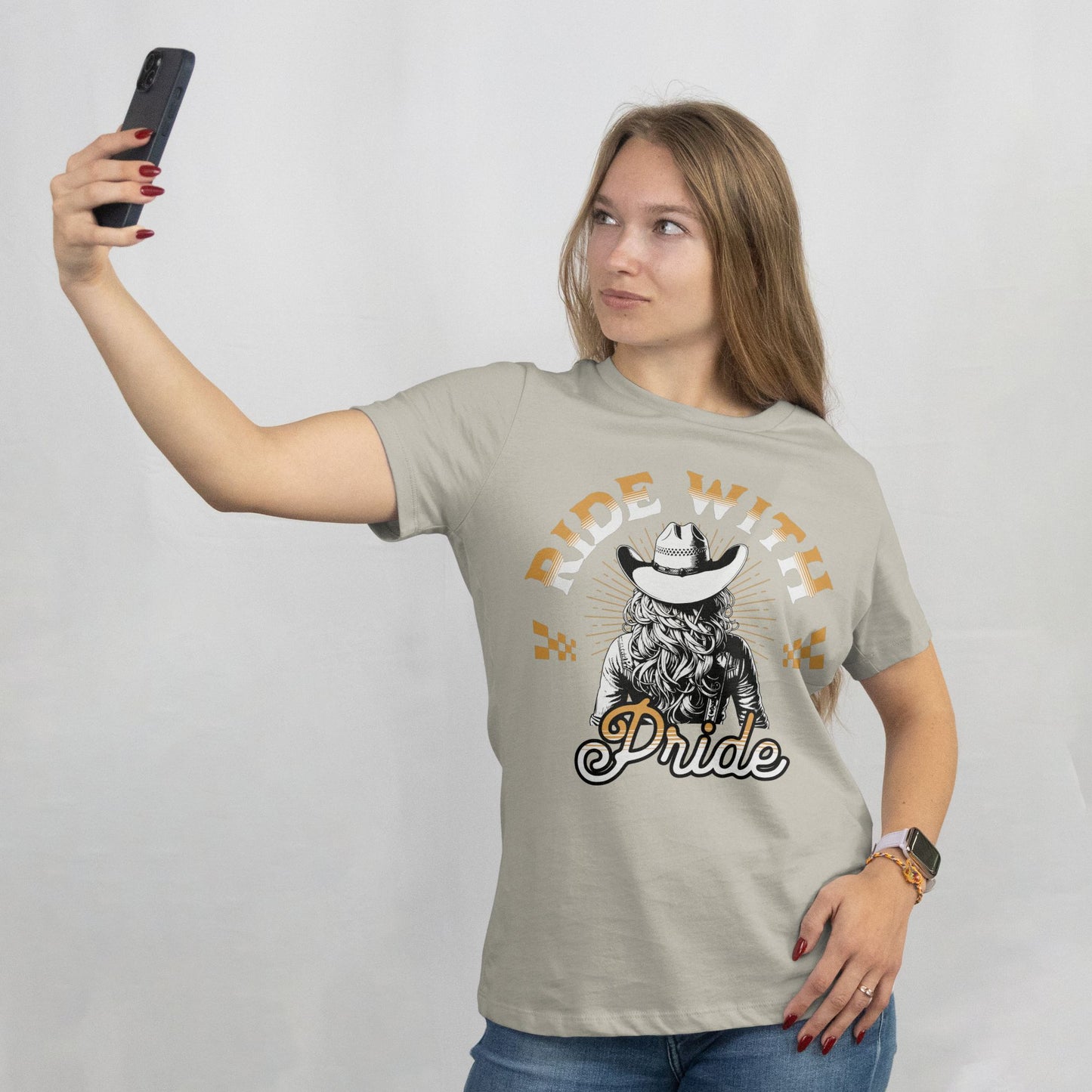 Woman wearing a t-shirt with a graphic design and text, taking a selfie against a plain background.
