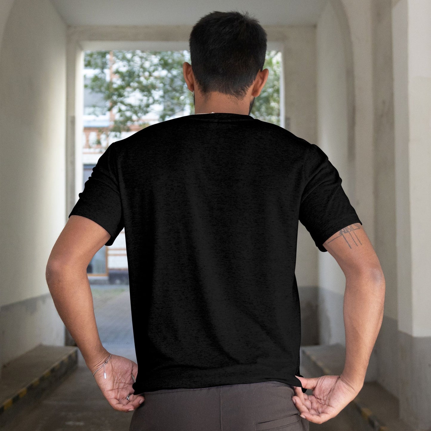 Person wearing a black t-shirt in an indoor setting with a window in the background