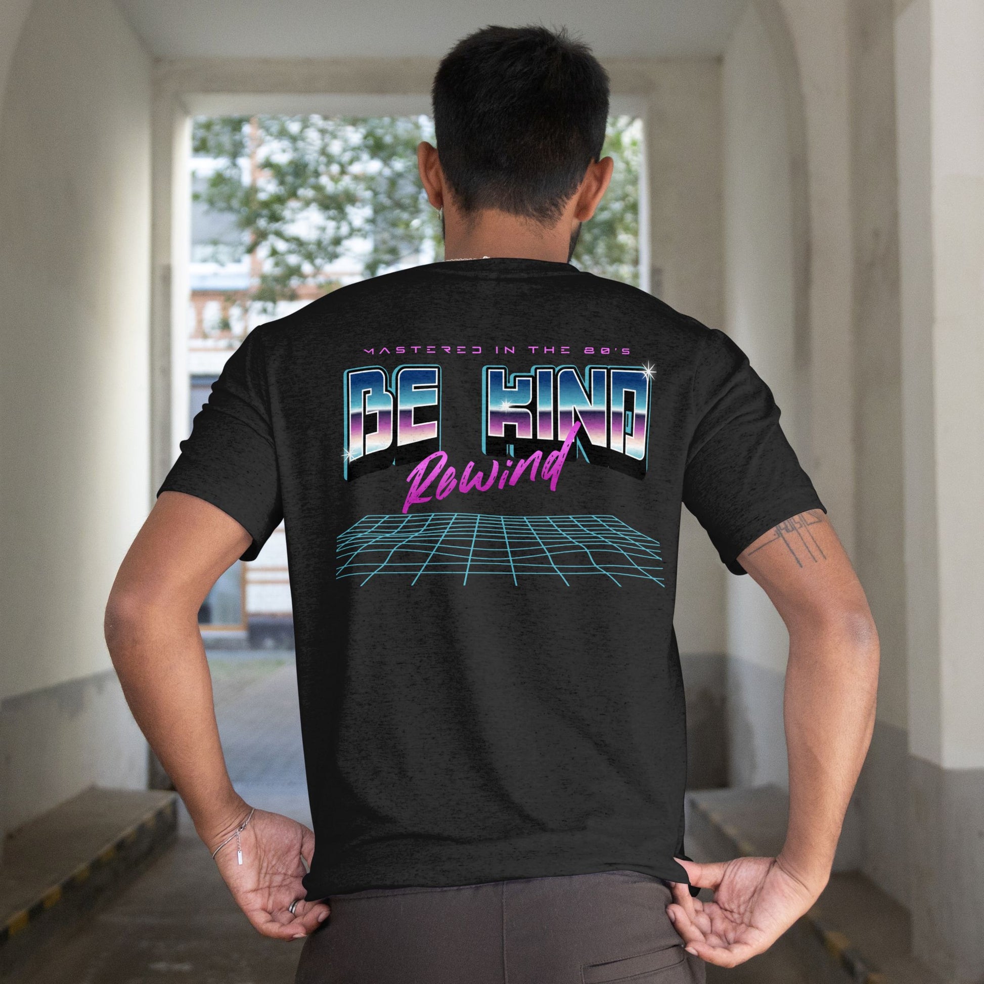 Person wearing a black t-shirt with colorful text and graphics on the back, standing in an indoor setting.