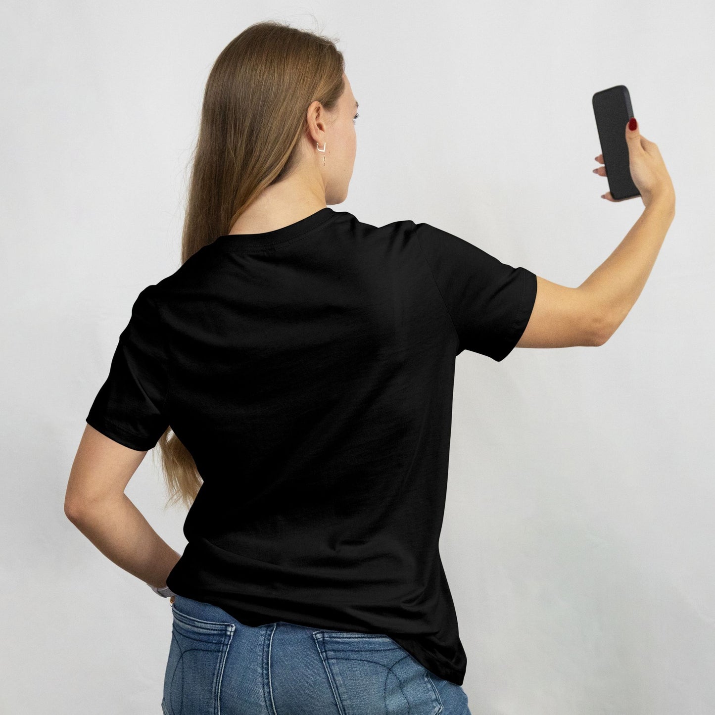 Person wearing a black t-shirt taking a selfie on a plain background