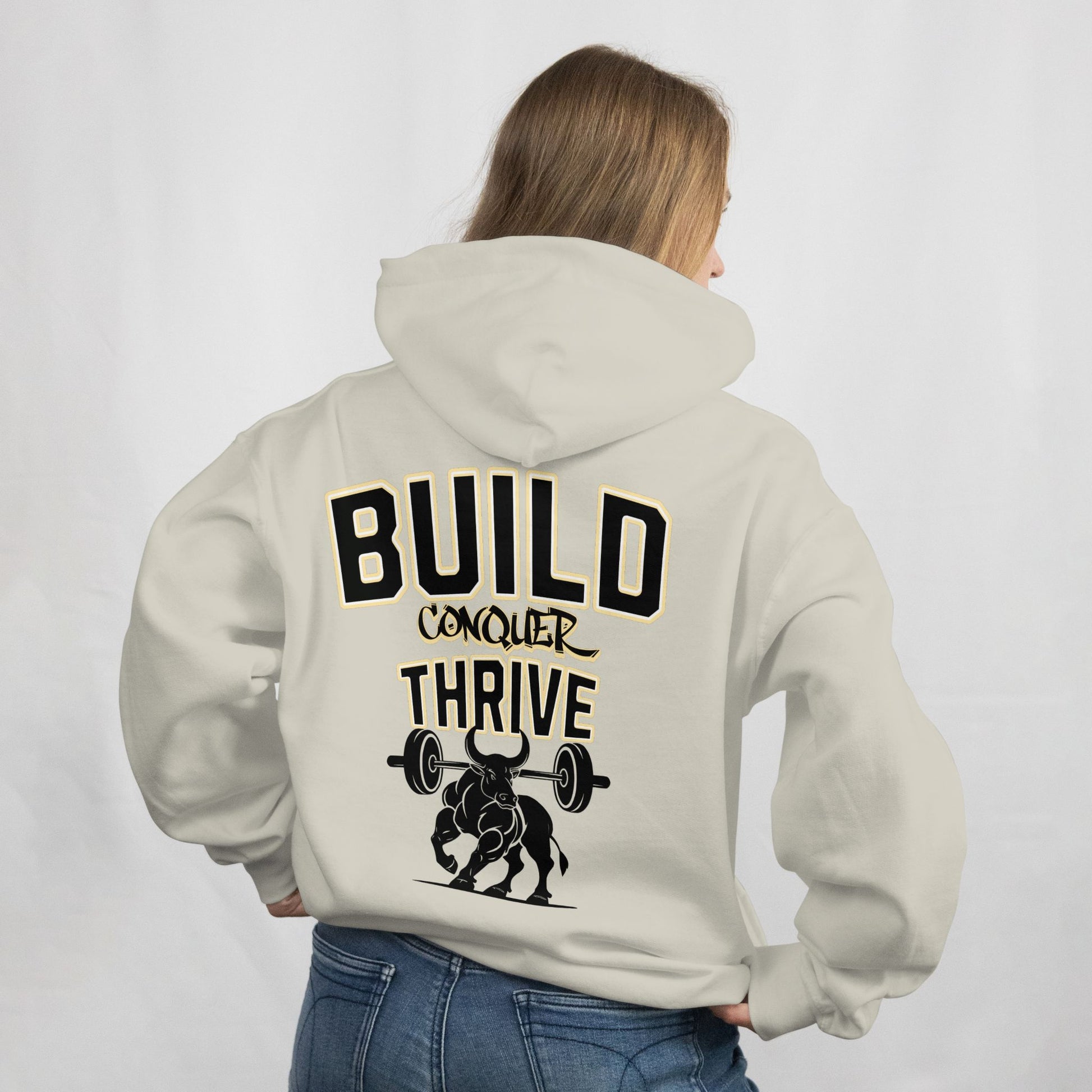 Person wearing a beige hoodie with motivational text and graphic on the back, standing against a plain background.