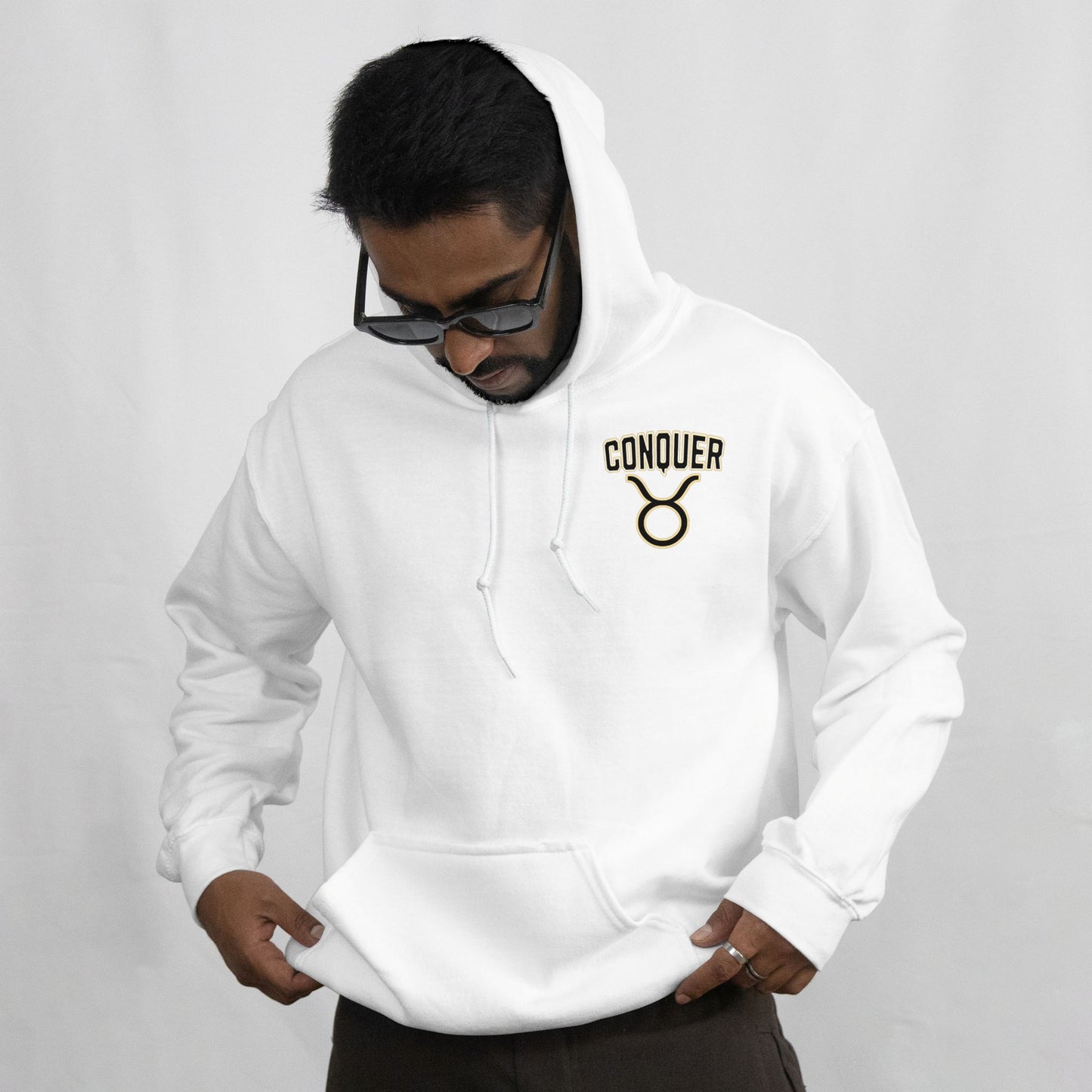 Person wearing a white hoodie with 'Conquer' logo on a gray background