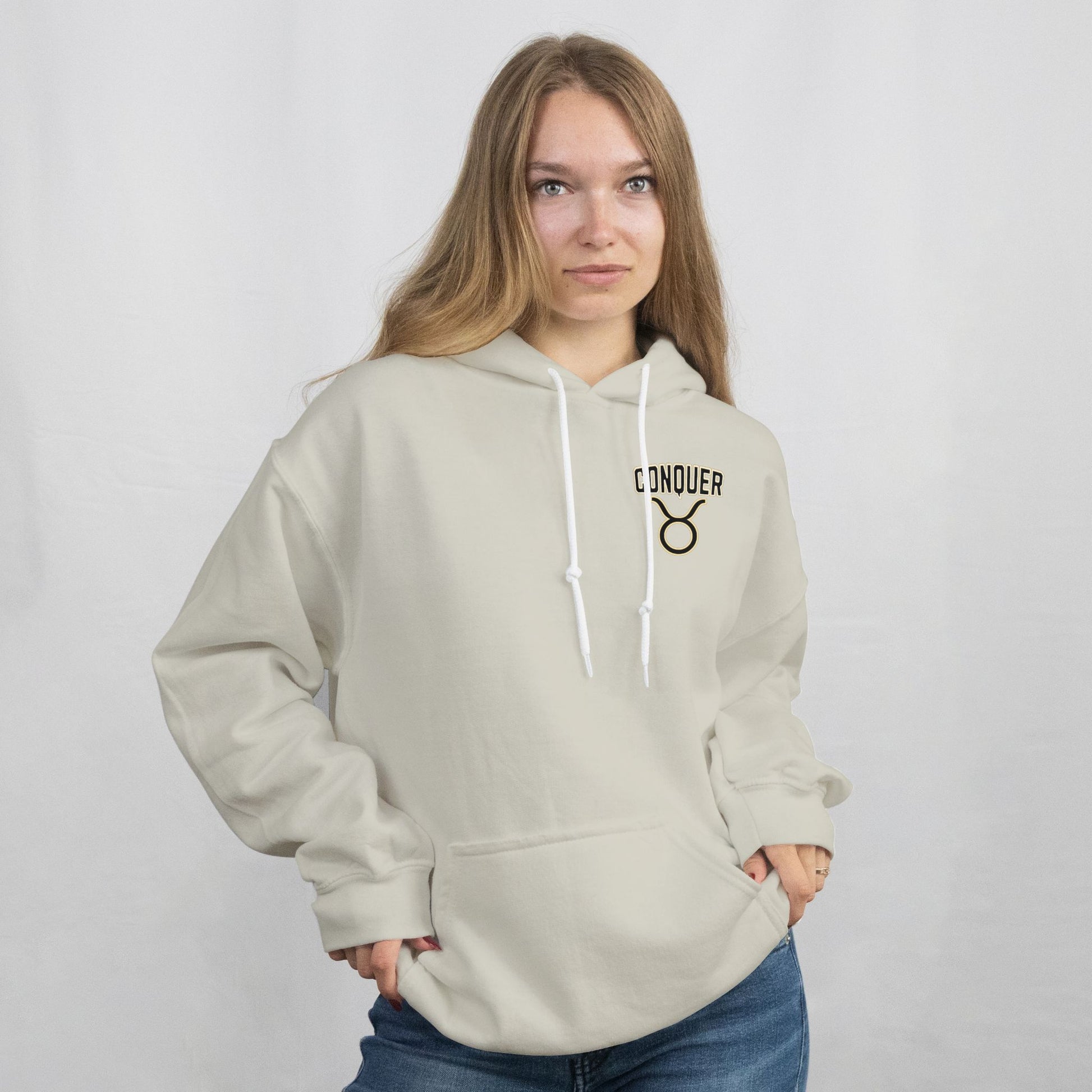 Woman wearing a beige hoodie with 'CONQUER' logo on a plain background