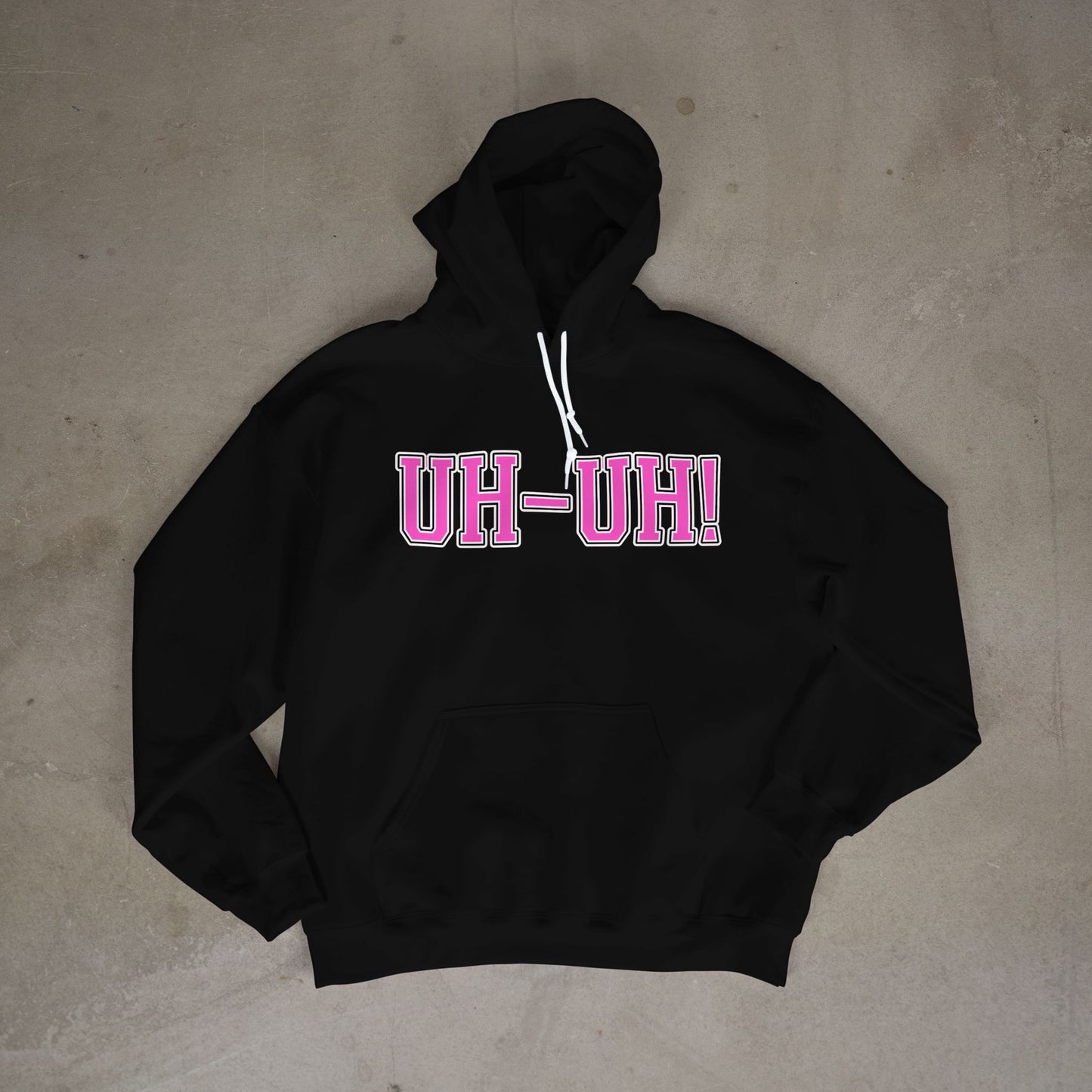 Black hoodie with 'UH-UH!' text in pink on a concrete floor.