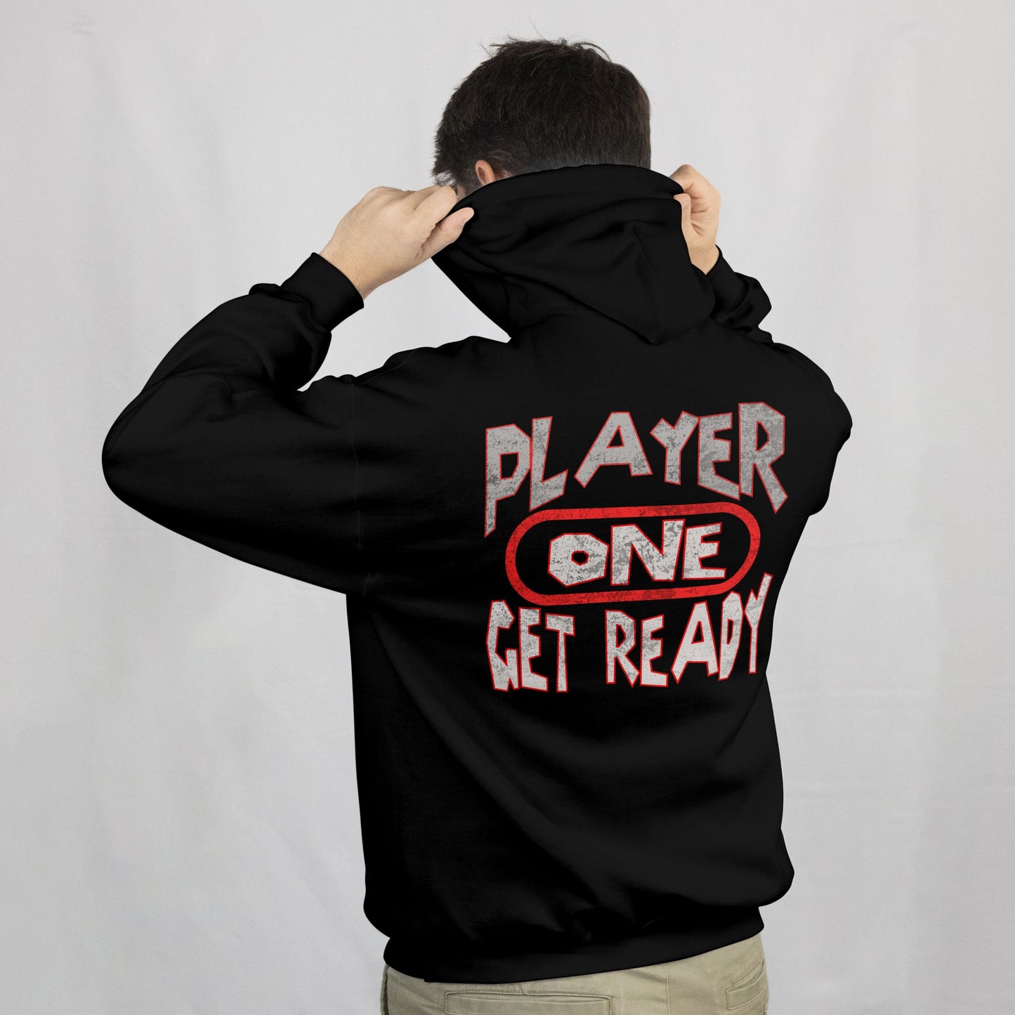 Person wearing a black hoodie with 'Player One Get Ready' text on the back against a plain background