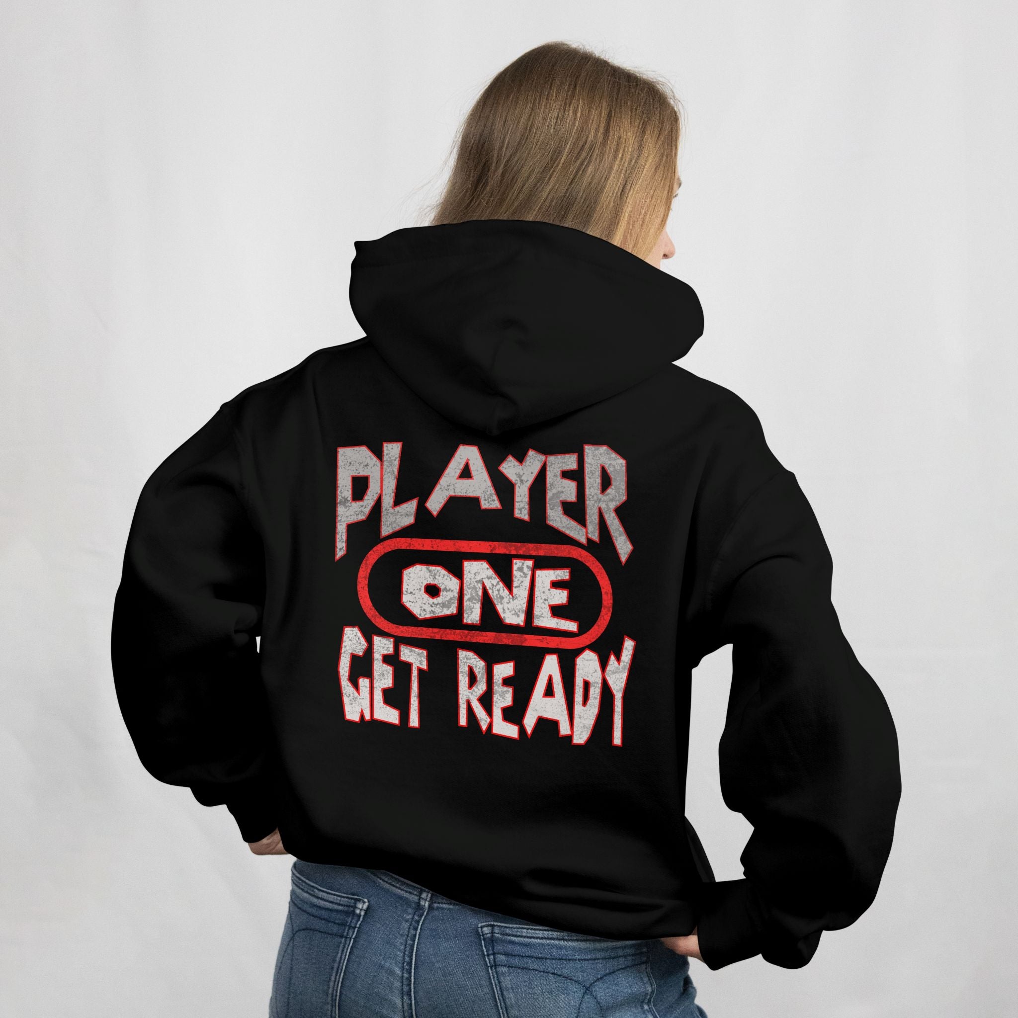 Person wearing a black hoodie with 'Player One Get Ready' text on the back against a white background
