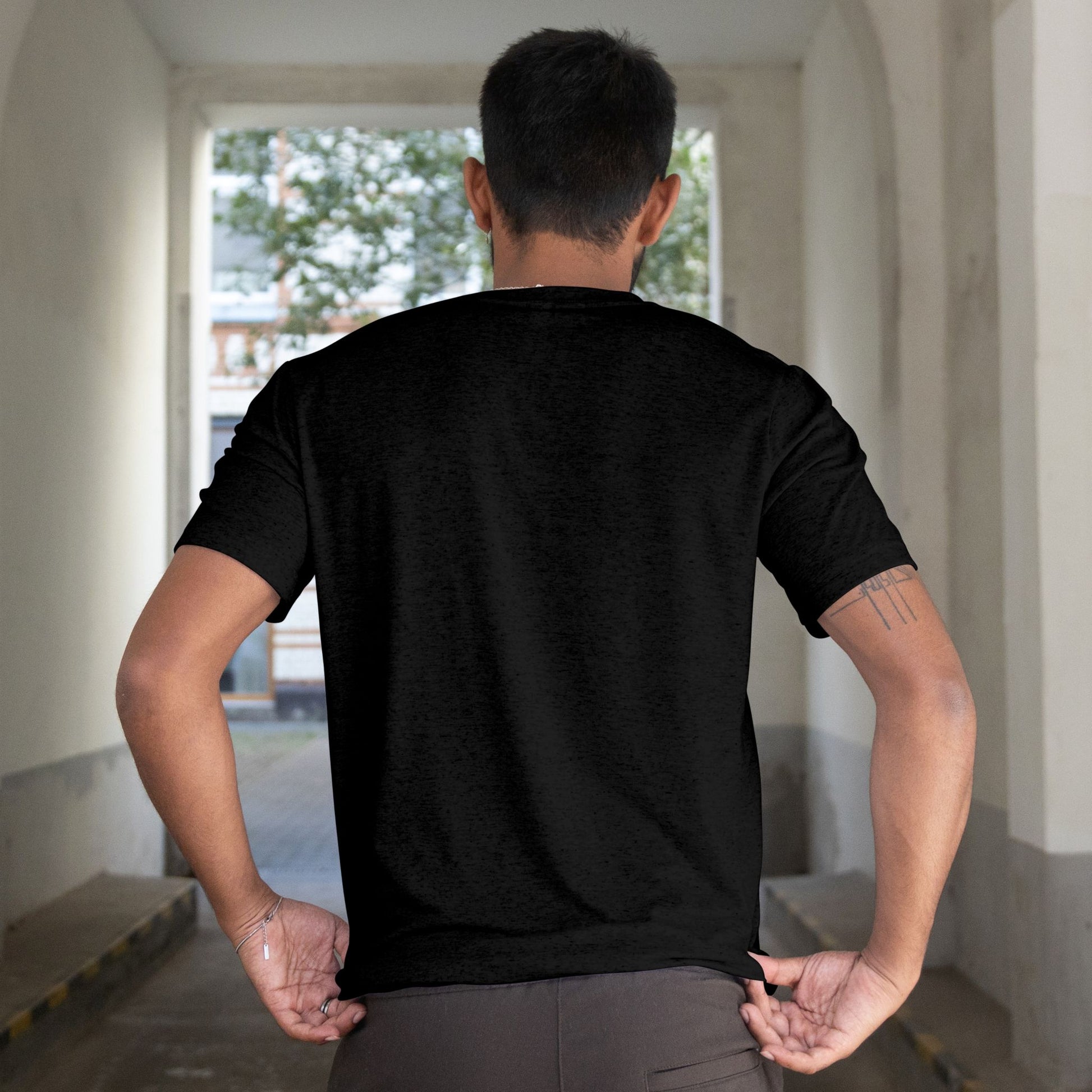 Person wearing a black t-shirt in an indoor setting with a window in the background