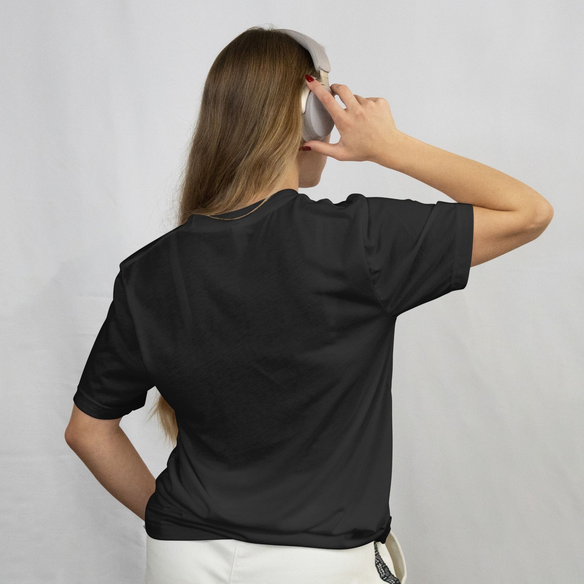 Person wearing a black t-shirt and white pants against a plain background